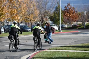 Two troopers assigned to policing at the Salt Lake Community College ride their bikes through the parking lot