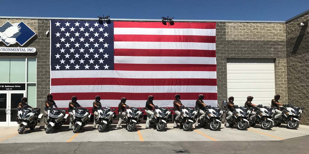 UHP motors line up in front of a large American flag in front of Eagle Environmental