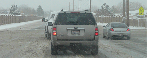 Vehicles drive on a slushy road way.