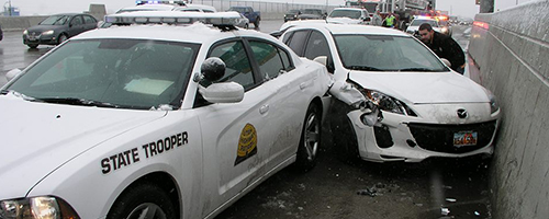 A car is wedged up against the median and is smashed into the back of a UHP charger