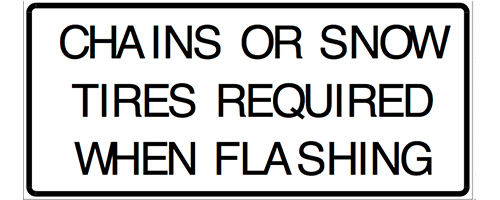 Image shows a sign that reads "Chains or snow tires required when flashing."