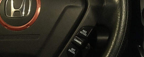 Close up shows a steering wheel with the cruise control levers.