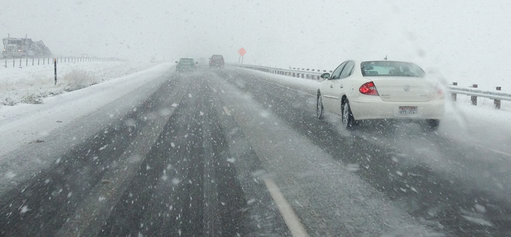 Car drive on a snowy road and snow is falling