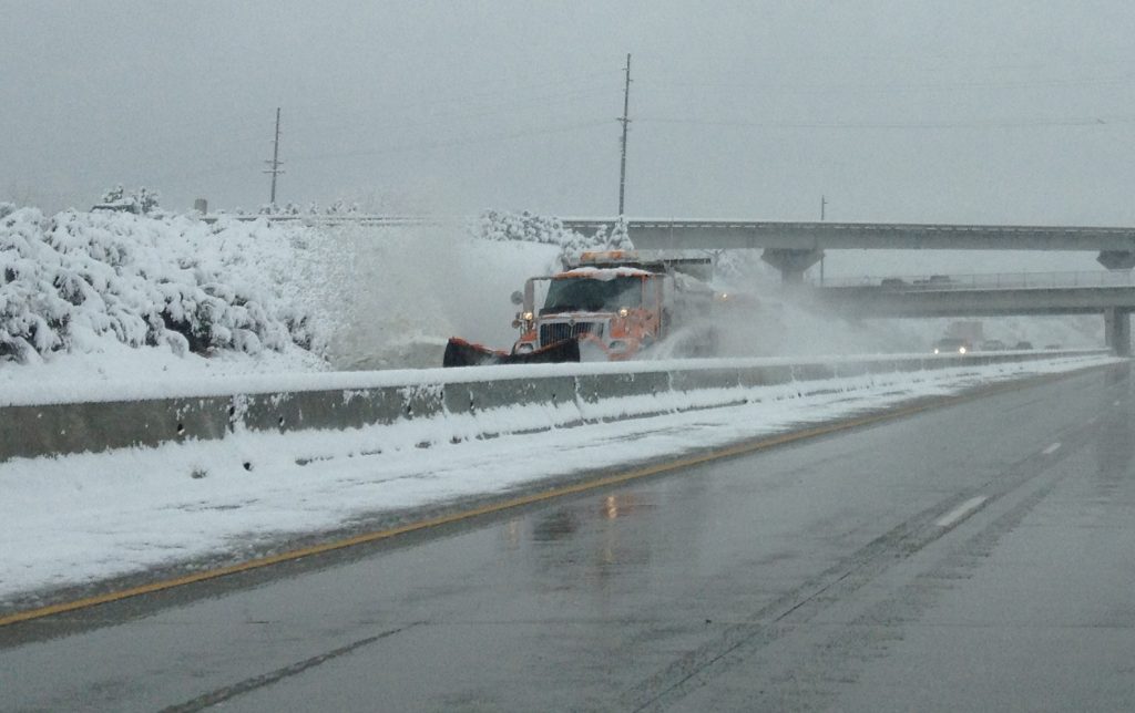 A snowplow is up against the median pushing snow.