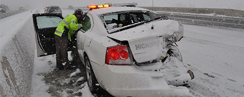 A trooper looks into his charger which has been smashed in on the right rear side.